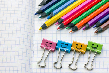 Color pencils and colored paper clips on a notebook sheet