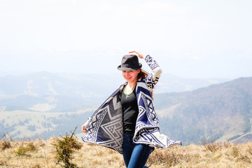 Rudy girl in the mountains in a poncho. Carpathian Mountains. Traveling tours