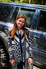 Rudy girl in the mountains in a poncho. Jeep car in the mountains. Woman near the car