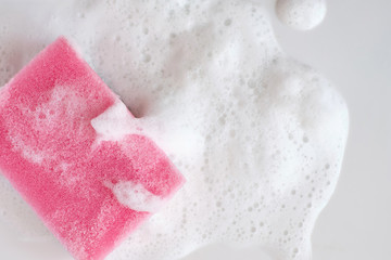 Pink sponge in the used sink full of foam