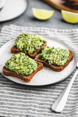 Three sandwiches with rye bread and mashed avocado on a plate. The concept of healthy vegetarian breakfast.