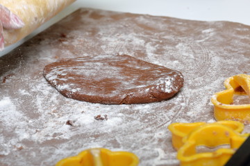 On the working surface of the table is rolled out dough. Everything is covered with flour. Near plastic mold and rolling pin.