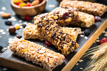 Granola bar with nuts, fruit and berries on black.