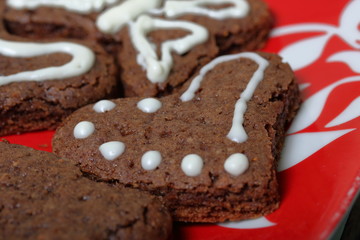 Baked gingerbread cookies are lying on a plate. Some are decorated with white icing. Cooking gingerbread.