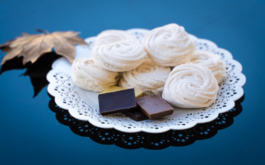 marshmallows and chocolate in a white plate on a dark background