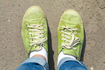 the old green gym shoes worn in spots with white laces. Footwear is put on standing. Top view