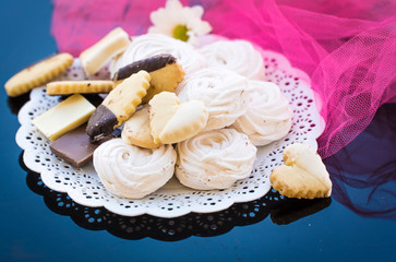marshmallows, biscuits and chocolate in a white plate on a background
