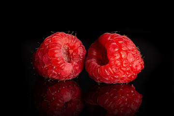 Group of two whole fresh red raspberry isolated on black glass