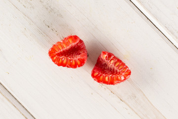Group of two halves of fresh red raspberry cross section flatlay on white wood