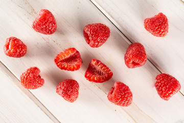 Group of lot of whole two halves of fresh red raspberry flatlay on white wood