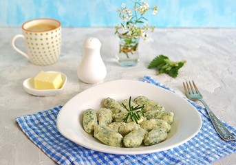 Gnocchi or dumplings with nettle or spinach on a white plate on a light gray background. Served with butter and parmesan cheese. Italian food. Selective focus