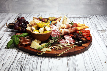 antipasto various appetizer. Cutting board with prosciutto, salami, cheese, bread and olives on white wooden background