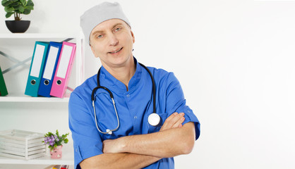 Portrait Of A Confident Mature Doctor Looking At Camera Isolated On Medical Office Background.