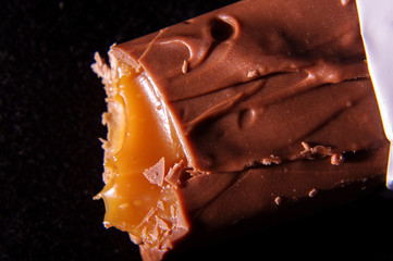 Bite off chocolate bar with tasty caramel macro close up