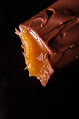 Bite off chocolate bar with tasty caramel macro close up