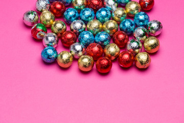 Chocolates in a multi-colored foil on a pink background