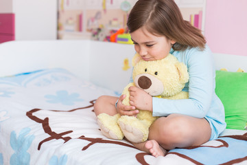 Cheerful little cute adorable baby girl playing with yellow teddy bear in her children room. Childhood, leisure kid time, happiness concept