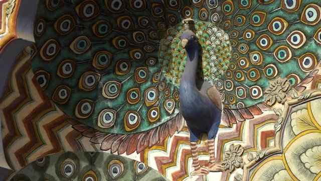 Extreme close up of a single carved peacock set in a vibrant mural above peacock gate at City Palace in Jaipur, India