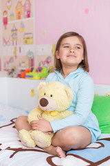 Cheerful little cute adorable baby girl playing with yellow teddy bear in her children room. Childhood, leisure kid time, happiness concept