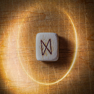 Dagaz. Handmade scandinavian wooden runes on a wooden vintage background in a circle of light. Concept of fortune telling and prediction of the future.