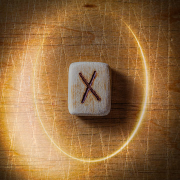 Gebo. Handmade scandinavian wooden runes on a wooden vintage background in a circle of light. Concept of fortune telling and prediction of the future.