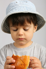 close up portrait of beautiful sweet boy, wearing denim bucket hat and grey t-shirt, eating a patty, long eyelashes, isolated on white background