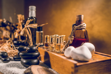 Fototapeta na wymiar Spa essential aromatic oil in vintage bottle and massage basalt zen stones and candles on the table