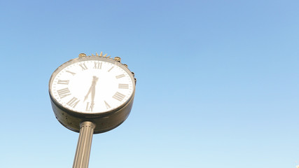 The big figured street clock against the blue sky