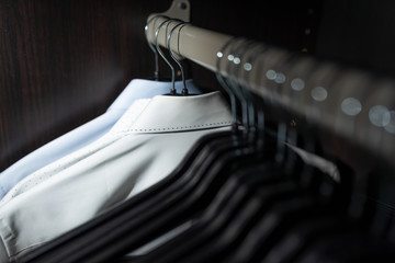Neat blouse in a mens wardrobe / closet with clothes hangers