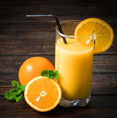 Fototapeta na wymiar Fresh orange juice in glass on wooden background
