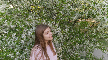 Young beautiful woman smells blooming sakura. Spring woman in cherry flower bloom. Happy mothers day or happy woman day. Outdoor lifestyle. Freedom concept