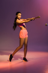 Fototapeta na wymiar attractive sportive african american girl playing baseball on purple background