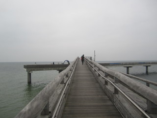 Fototapeta na wymiar Frau auf Seebrücke vor Horizont