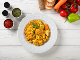 A plate of chicken curry sauce with vegetables served on the table