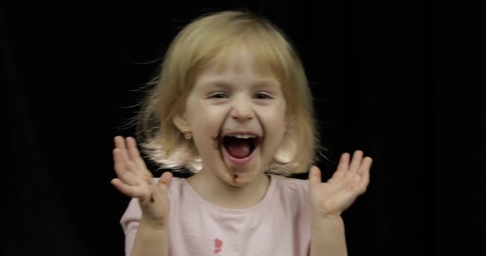 Child with dirty face from melted chocolate and whipped cream smiling
