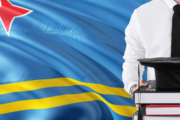 Successful student education concept. Holding books and graduation cap over Aruba flag background.