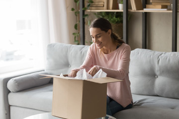 Client woman sitting on couch unbox carton box feels satisfied