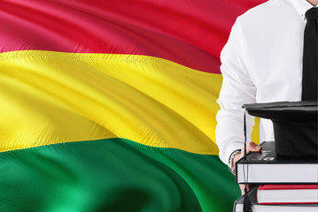 Successful Bolivian student education concept. Holding books and graduation cap over Bolivia flag background.