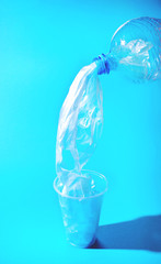 Plastic artificial water running from the bottle in a cup.