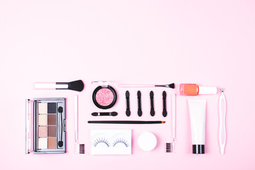 Make-up woman essentials on pink background.