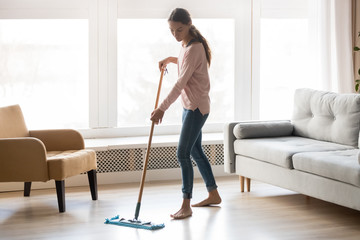 Barefoot girl doing house cleaning using microfiber wet mop pad