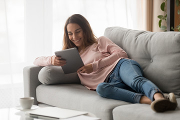 Fototapeta na wymiar Woman lying on couch with tablet spending time at home