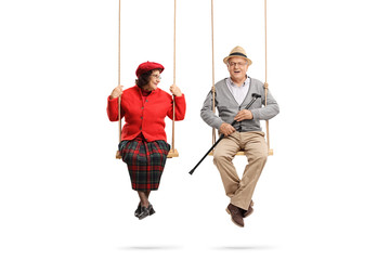 Senior woman on a swing looking at a senior man on a swing