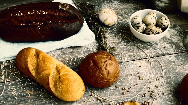 Different types of bread on wooden table dusted with flour. Slow pan. Closeup. Selective focus, Copy space.