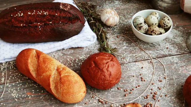 Different types of bread on wooden table dusted with flour. Slow pan. Closeup. Selective focus, Copy space.