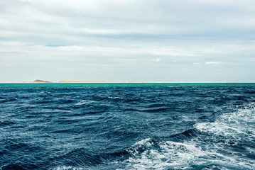minimalistic seascape, blue sea and sky with white clouds on the whole frame