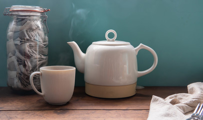 Cup and jar of hot English tea on the wooden table. Vintage background style.