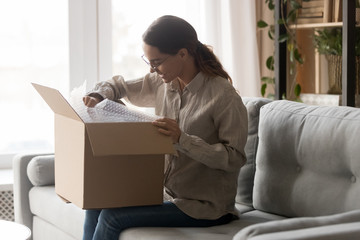 Woman holds big carton box on laps unpack delivered goods