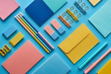 top view of notebooks and arranged colorful stationery isolated on blue - obrazy, fototapety, plakaty