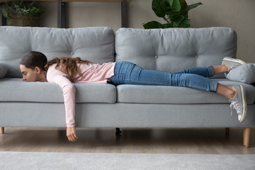 Young woman lying buried her face in sofa feels tired